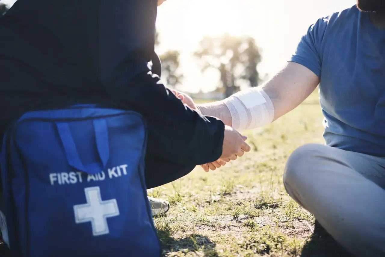 First aid kit / responder hands (top cropped; dark bag with white KIT lettering visible).