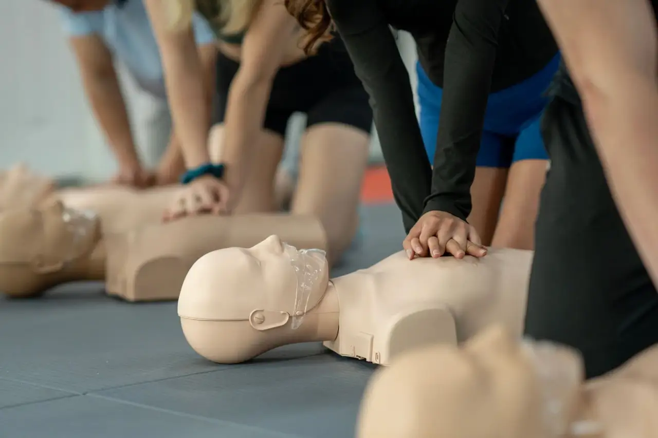 CPR manikin with breathing mask/airway, hands on chest (class close-up).