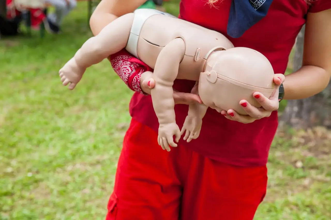 Adult holding a baby/infant (red clothing, close-up of hands and baby).